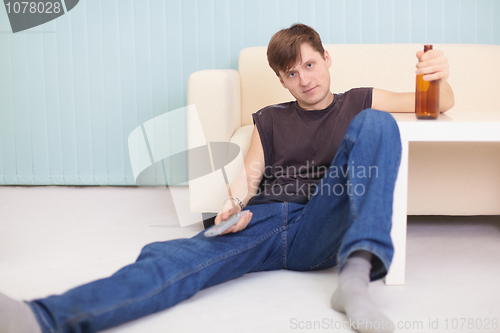 Image of Person sits on floor with beer - house rest