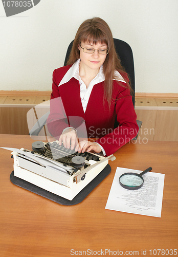 Image of Serious woman secretary printing text on typewriter