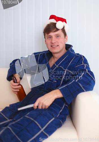 Image of Person in red santa s cap sits on sofa