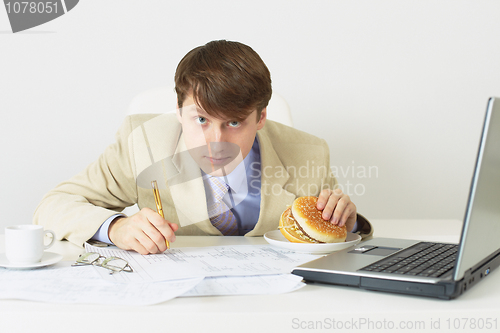 Image of Person with the big sandwich in hand sits on a workplace