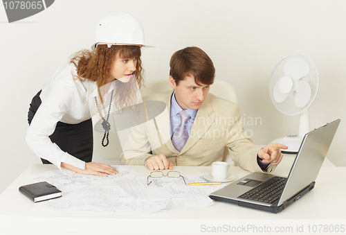 Image of Two young engineers work over project on laptop