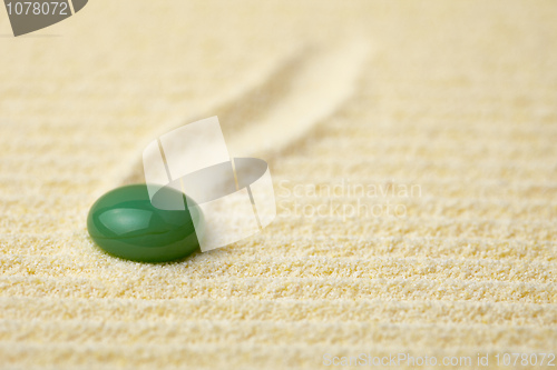 Image of Green stone on a surface of yellow sand