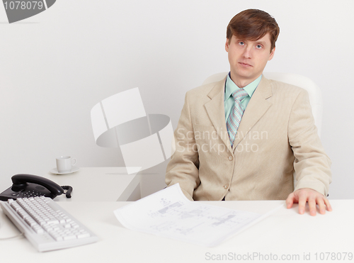 Image of Serious businessman sits on workplace at office