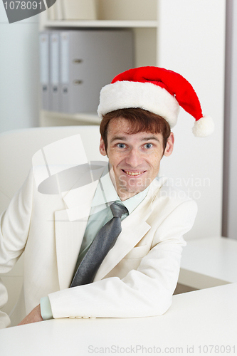 Image of Happy man in Christmas cap at office