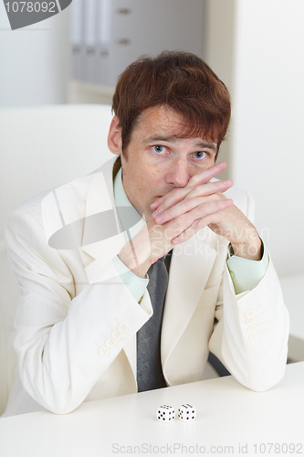 Image of Young businessman in white suit sits at a table