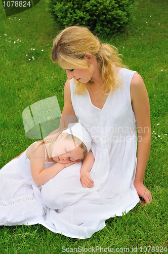 Image of Young mother and daughter resting in meadow