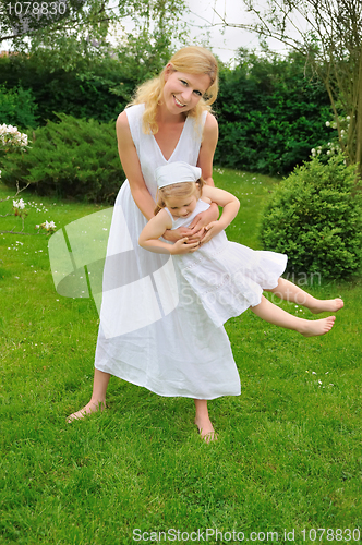 Image of Young mother and daughter playing in meadow