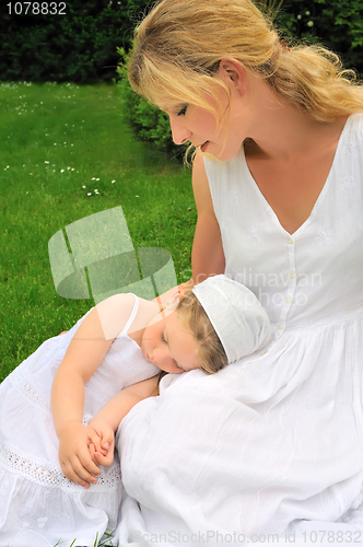 Image of Young mother and daughter resting in meadow