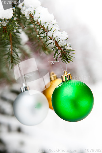 Image of Christmas baubles on a snowy pine