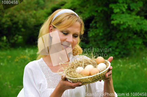 Image of Happy young woman holding fresh eggs