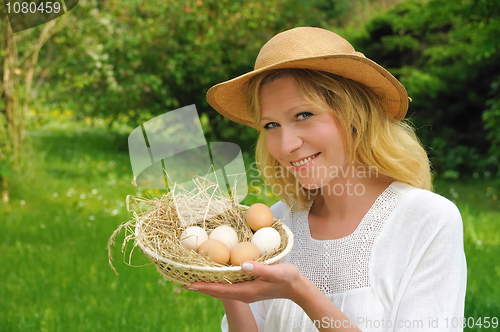 Image of Happy young woman holding fresh eggs