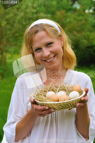 Image of Happy young woman holding fresh eggs