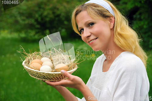 Image of Happy young woman holding fresh eggs