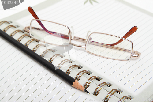 Image of A diary, pencil and glasses