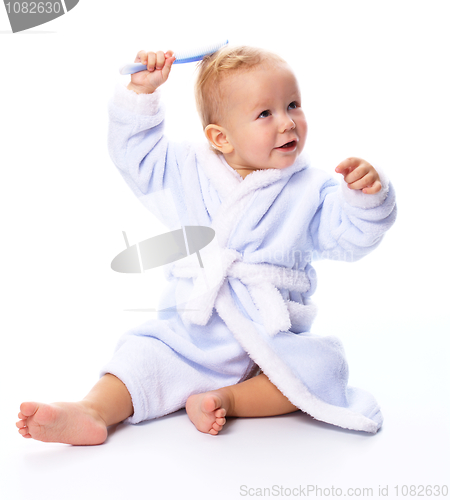 Image of Cute child in bathrobe with comb