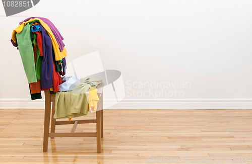 Image of Wooden chair with messy clothes on it