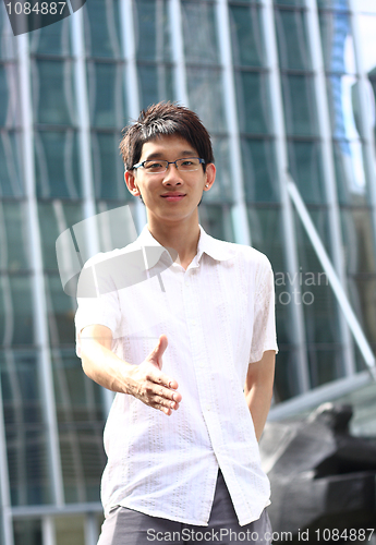 Image of Asian Businessman offering for handshake, office building as bac