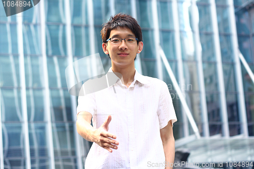 Image of Asian Businessman offering for handshake, office building as bac