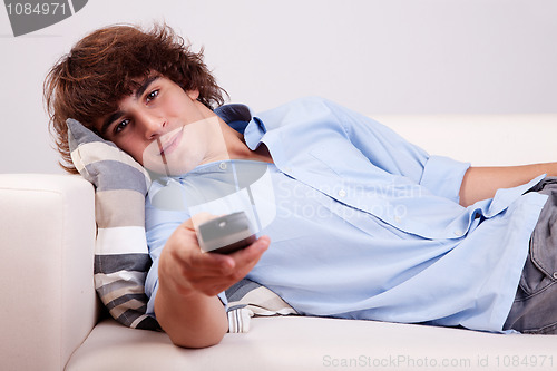 Image of young man, watching television with the command at hand
