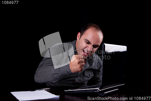 Image of furious businessman looking to computer and taking notes