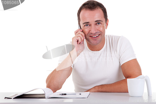 Image of smiling middle-age man sitting at desk on the phone