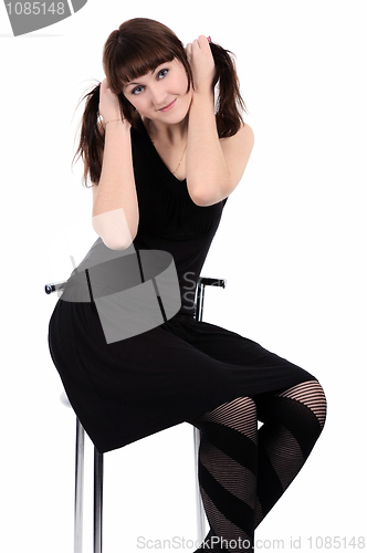 Image of Girl in black dress sitting on a high chair, isolated