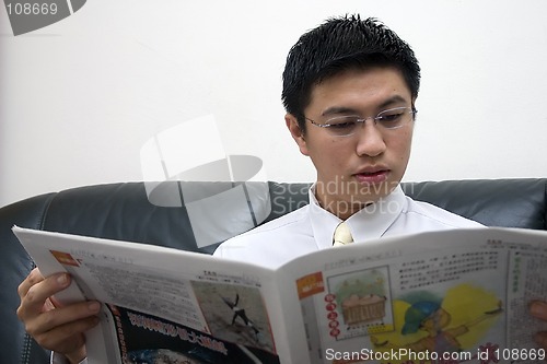 Image of Young Asian Entrepreneur Reading Newspaper