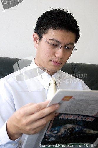 Image of Young Asian Entrepreneur Reading Newspaper