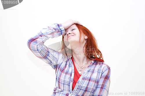 Image of Redhead young woman holding her hand to the head