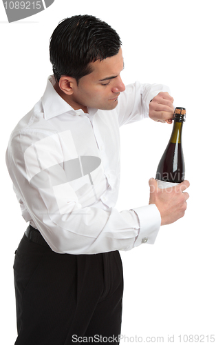 Image of Sideview man or waiter opening bottle of champagne