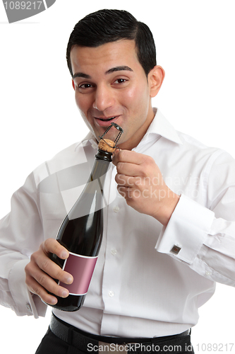 Image of Happy man opening sparkling wine or champagne