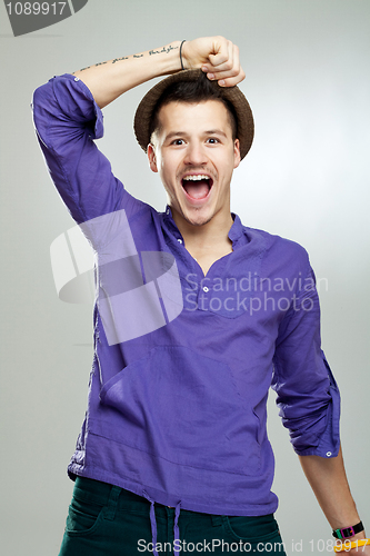 Image of excited young man wearing a hat