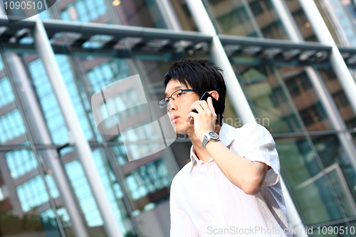 Image of young businessman in a suit holding mobile phone in front of mod