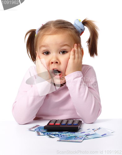 Image of Little girl plays with money, making shocked face