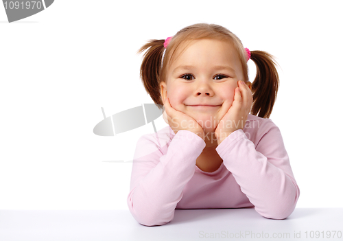 Image of Happy little girl sits at a table and smile