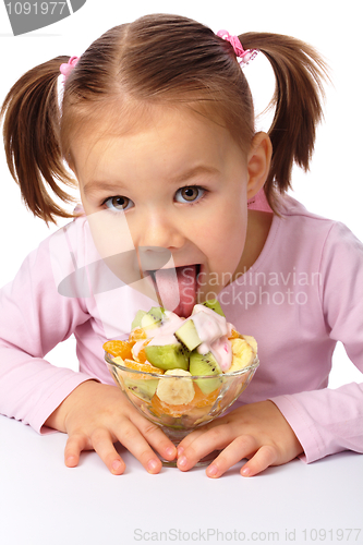 Image of Little girl licks fruit salad