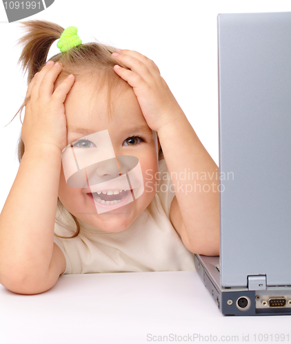 Image of Cute little girl is looking out from her laptop