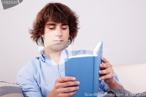 Image of man seated reading a book on couch