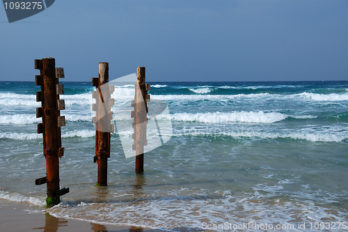 Image of Old rusty pier piles on sea shore