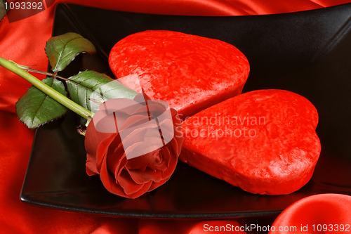 Image of Two red heart shaped cakes and a rose