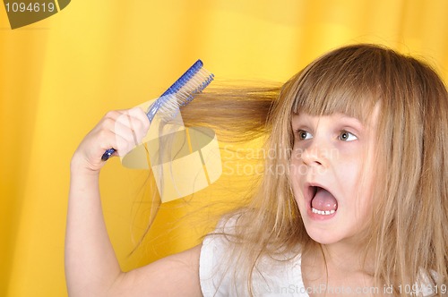 Image of child having problem with brushing her hair