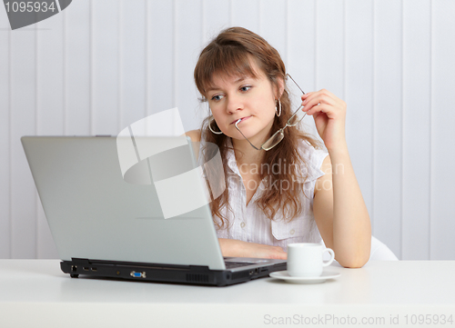 Image of Young woman working with laptop computer at table with coffee