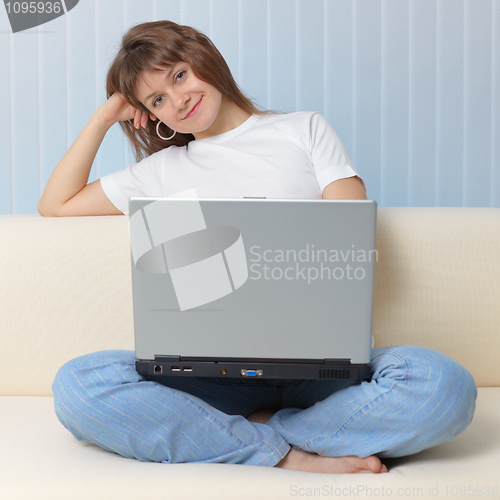 Image of Beautiful young girl with laptop has rest sitting on a sofa