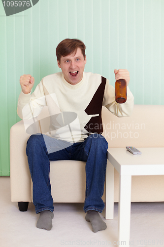 Image of Football fan sitting on sofa with TV