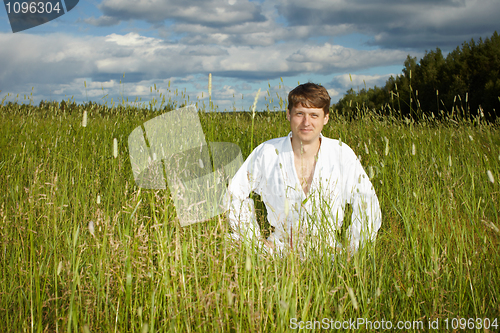 Image of Young man in white kimono sits in grass