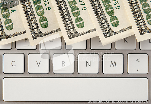 Image of Hundred dollar bills on computer keyboard with spacebar