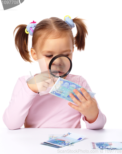 Image of Girl is looking at euro banknote using magnifier