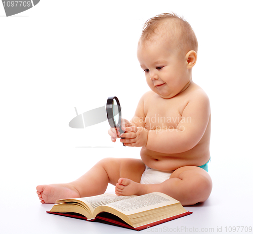 Image of Little child play with book and magnifier