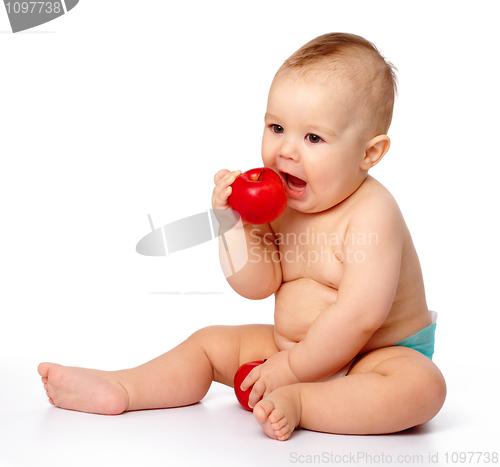 Image of Little child is going to bite red apple