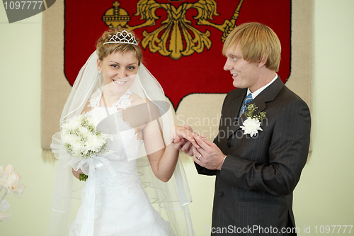 Image of Groom solemnly puts ring on bride